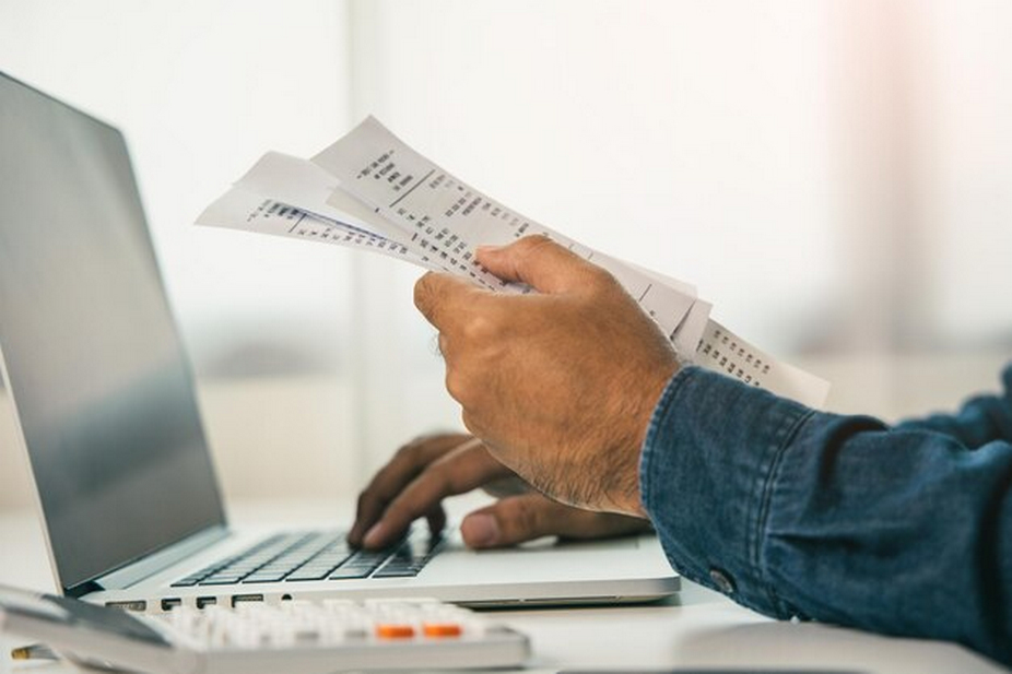 Person using laptop while holding receipts